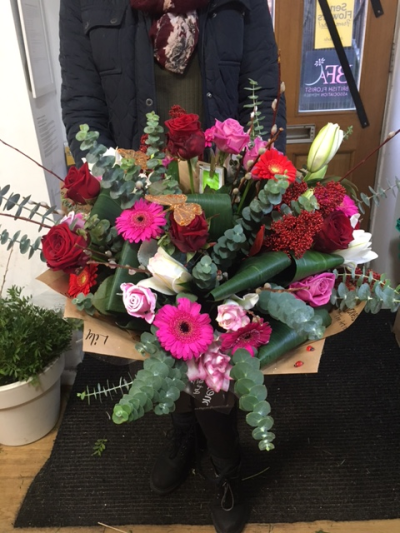 Riches - This rich vibrant red and cerise bouquet contains roses, gerberas  and complimenting flowers in burgundy, dark red, wine and deep pink shades.